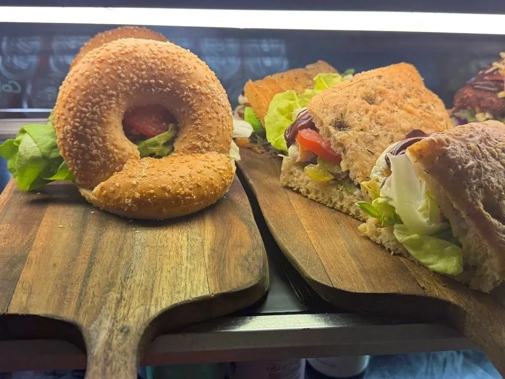 Filled bagel and focaccia sandwiches on wooden boards